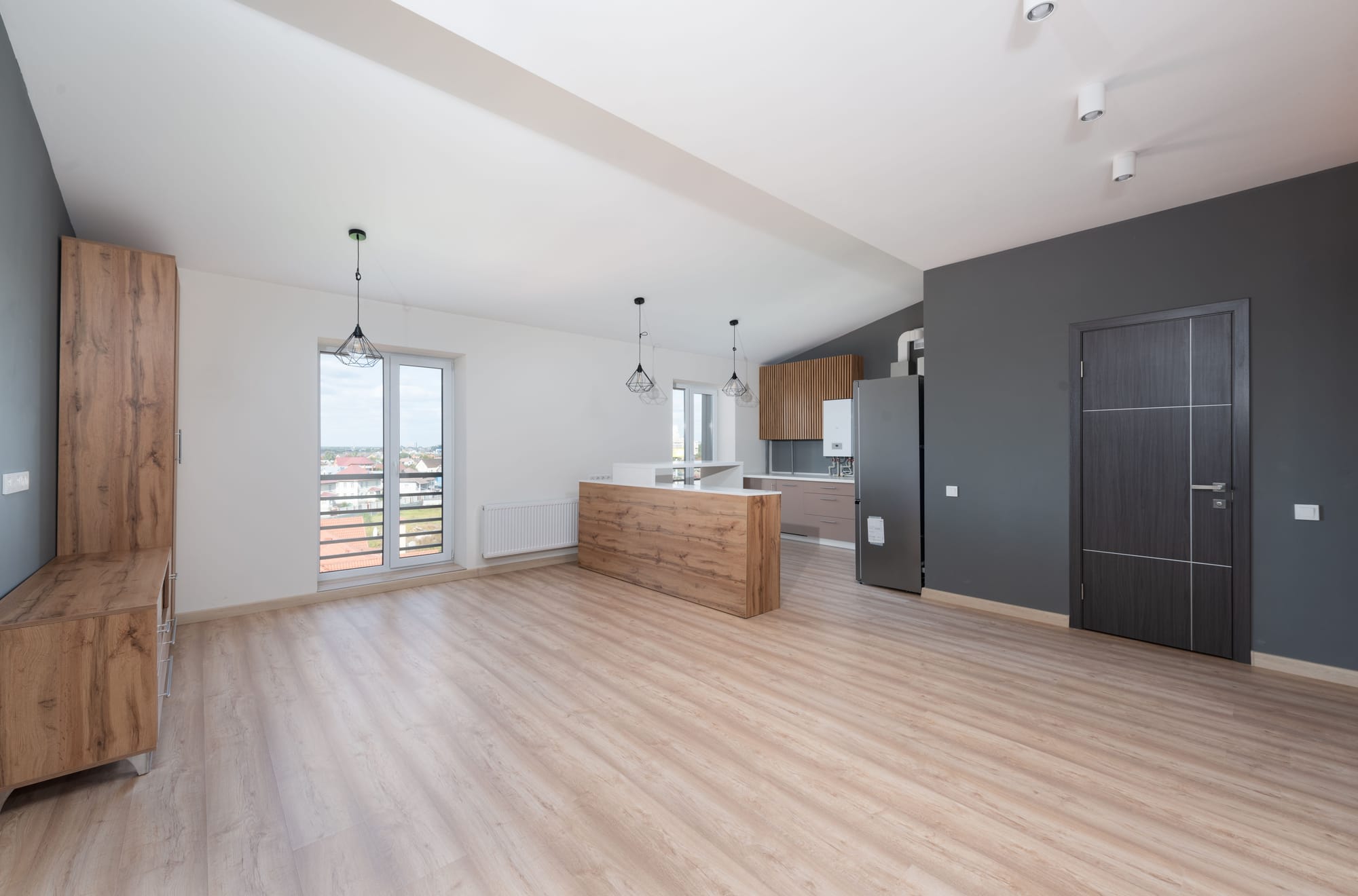 Light wood-look flooring in a bright, open Las Vegas apartment with a kitchen and large window