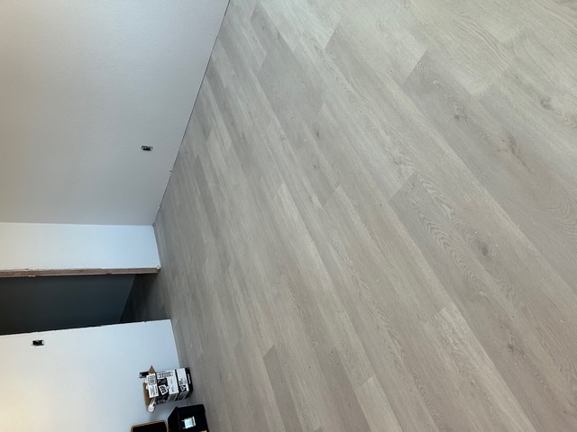 Wide greige wood-look laminate flooring in a clean, empty Las Vegas room