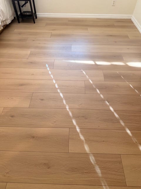 Finished warm oak wood flooring in a sunlit Las Vegas bedroom